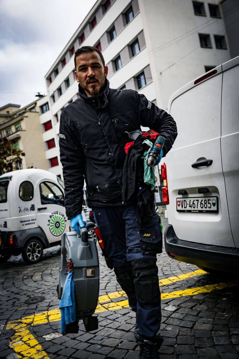 Monteur Henchoz arrivant devant un immeuble avec son matériel